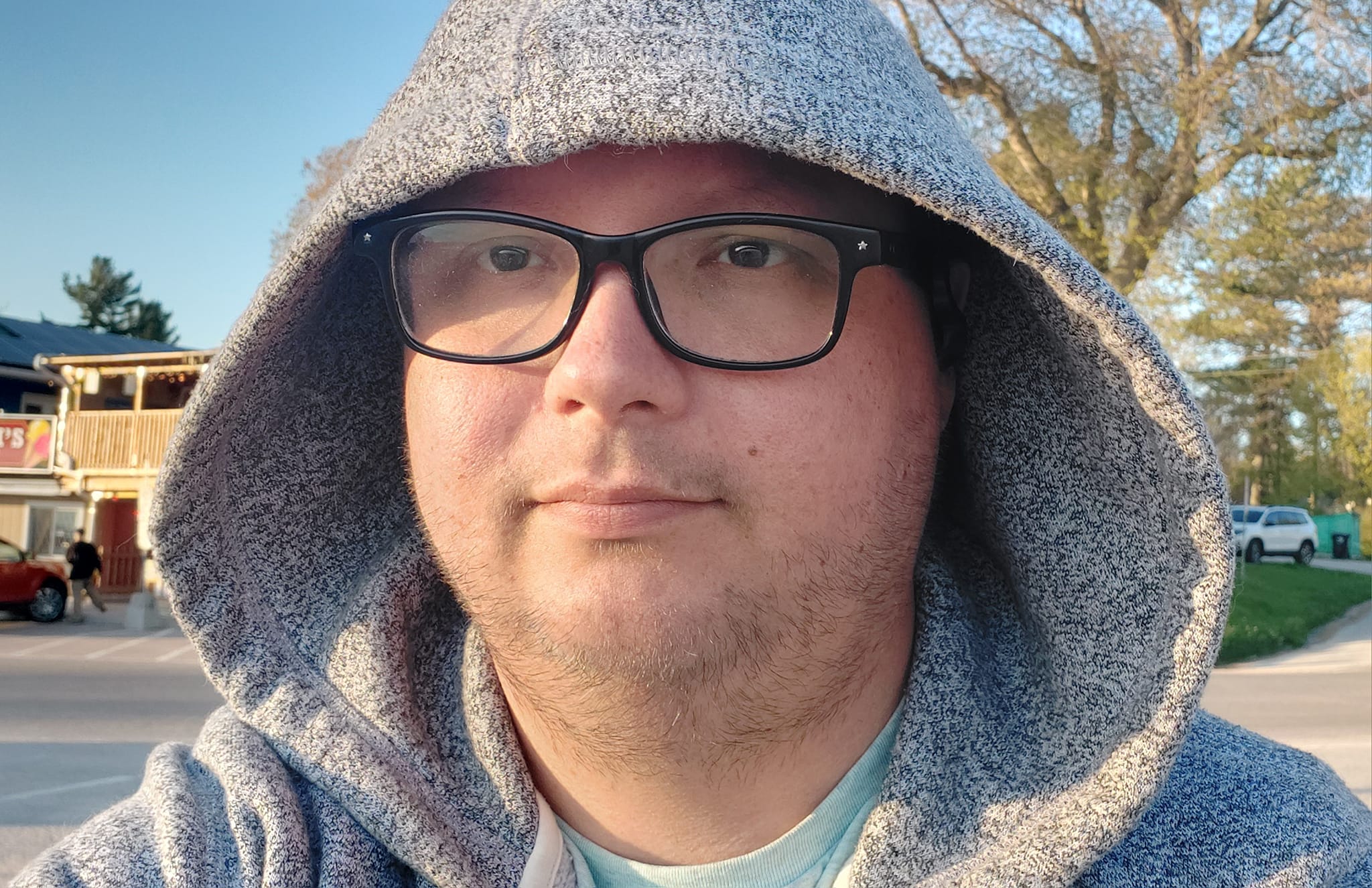 A man wearing a sweater sits outside in front of a convienence store by the beach